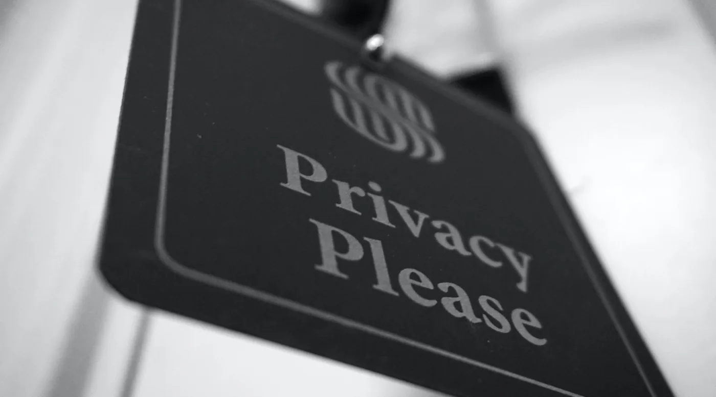 Close-up of a black door sign that reads “Privacy Please”.